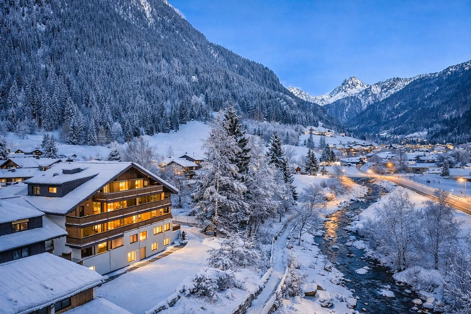Aparthotel die Monika in Gaschurn im Winter — warm beleuchtet, umgeben von verschneiter Berglandschaft
